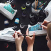 Hands are applying leather pigment dye to a white sneaker, demonstrating DIY art projects.