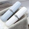 A white and light blue dust-proof toothbrush travel case with a vented cover resting on a gray towel.