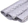 A stack of silver quilted ironing mats for wrinkle removal.