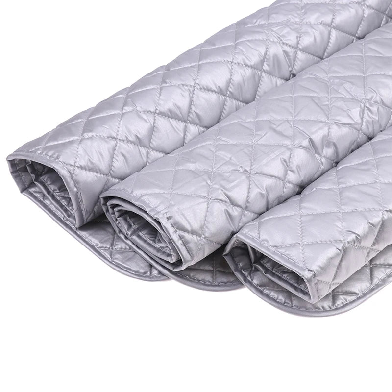 A stack of silver quilted ironing mats for wrinkle removal.