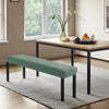 A teal stretch jacquard bench cover placed on a light gray rug in a modern living room.