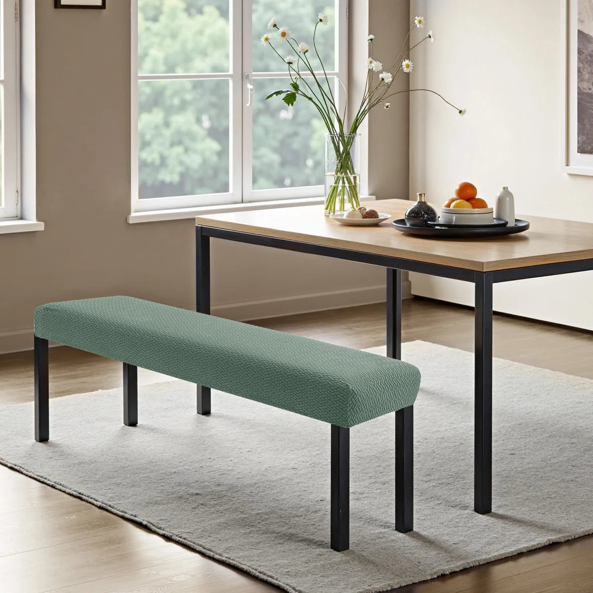A teal stretch jacquard bench cover placed on a light gray rug in a modern living room.