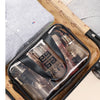 A transparent PVC travel toiletry bag with wet-dry separation is shown resting on a patterned fabric and clothing.