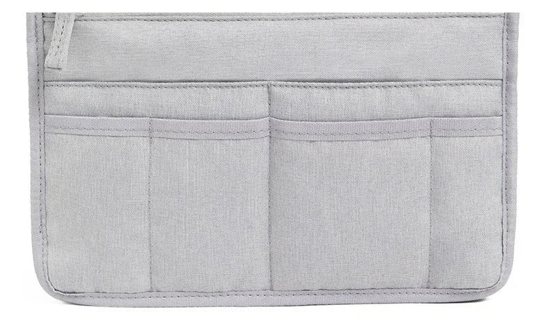 A light gray purse organizer insert with multiple stitched compartments.