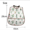 A white baby feeding bib featuring a pattern of green cacti and a pink trim.