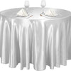 A round silver satin tablecloth set for events featuring glassware and napkins.