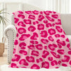 A pink leopard print flannel throw blanket draped over a light-colored sofa.