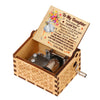 A hand-cranked wooden music box with a floral engraved lid and a small metal mechanism.