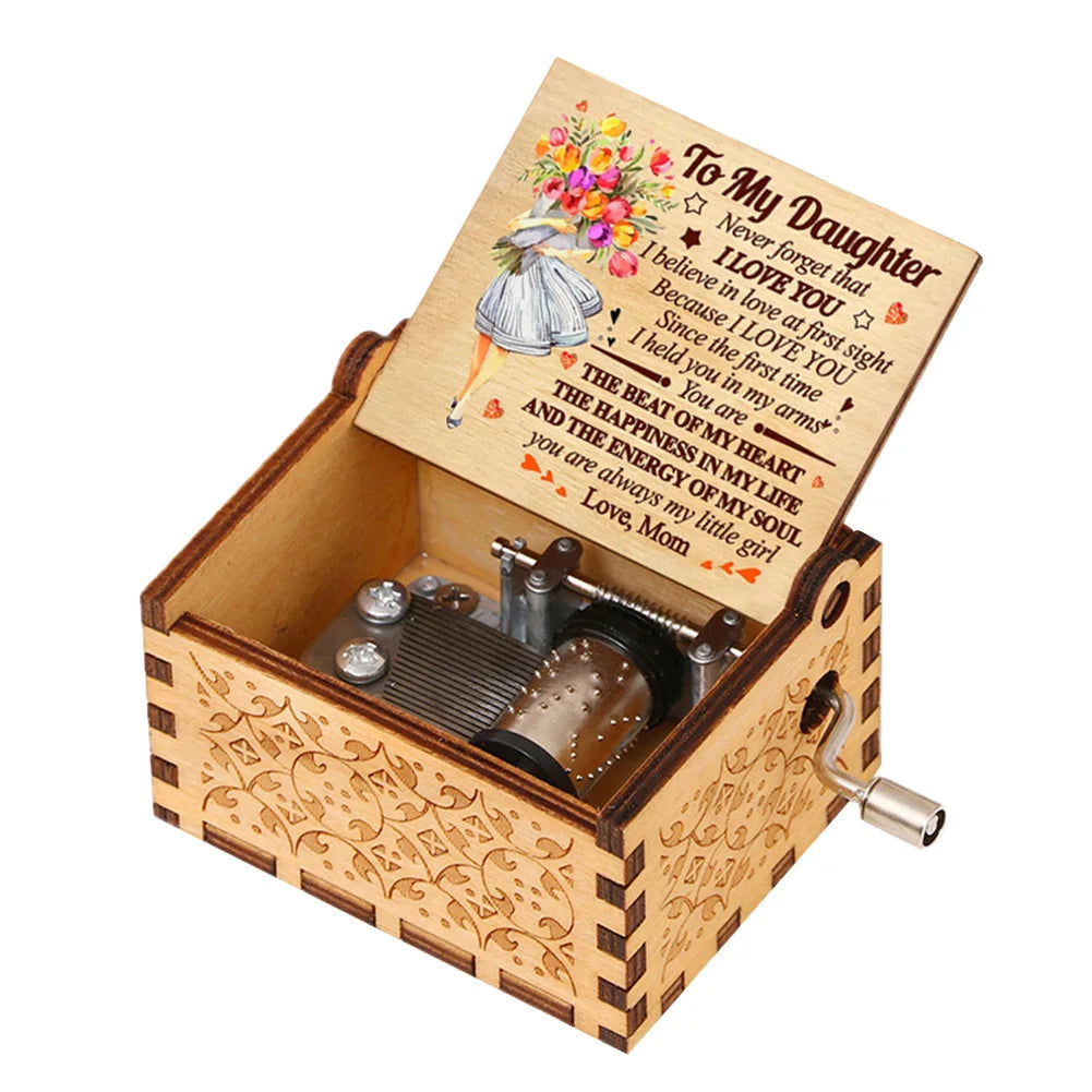 A hand-cranked wooden music box with a floral engraved lid and a small metal mechanism.