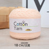 A skein of light pink cotton yarn labeled as Cotton Yarn 100g, resting on a wooden surface.