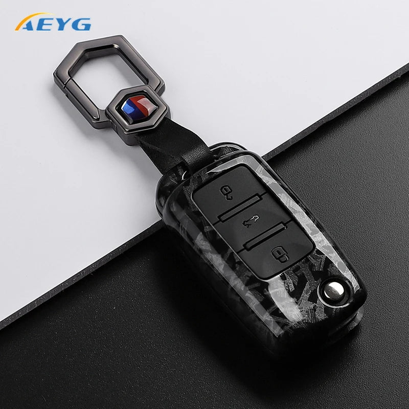 A carbon fiber car key cover with a metal loop and electronic features for VW and Skoda models.