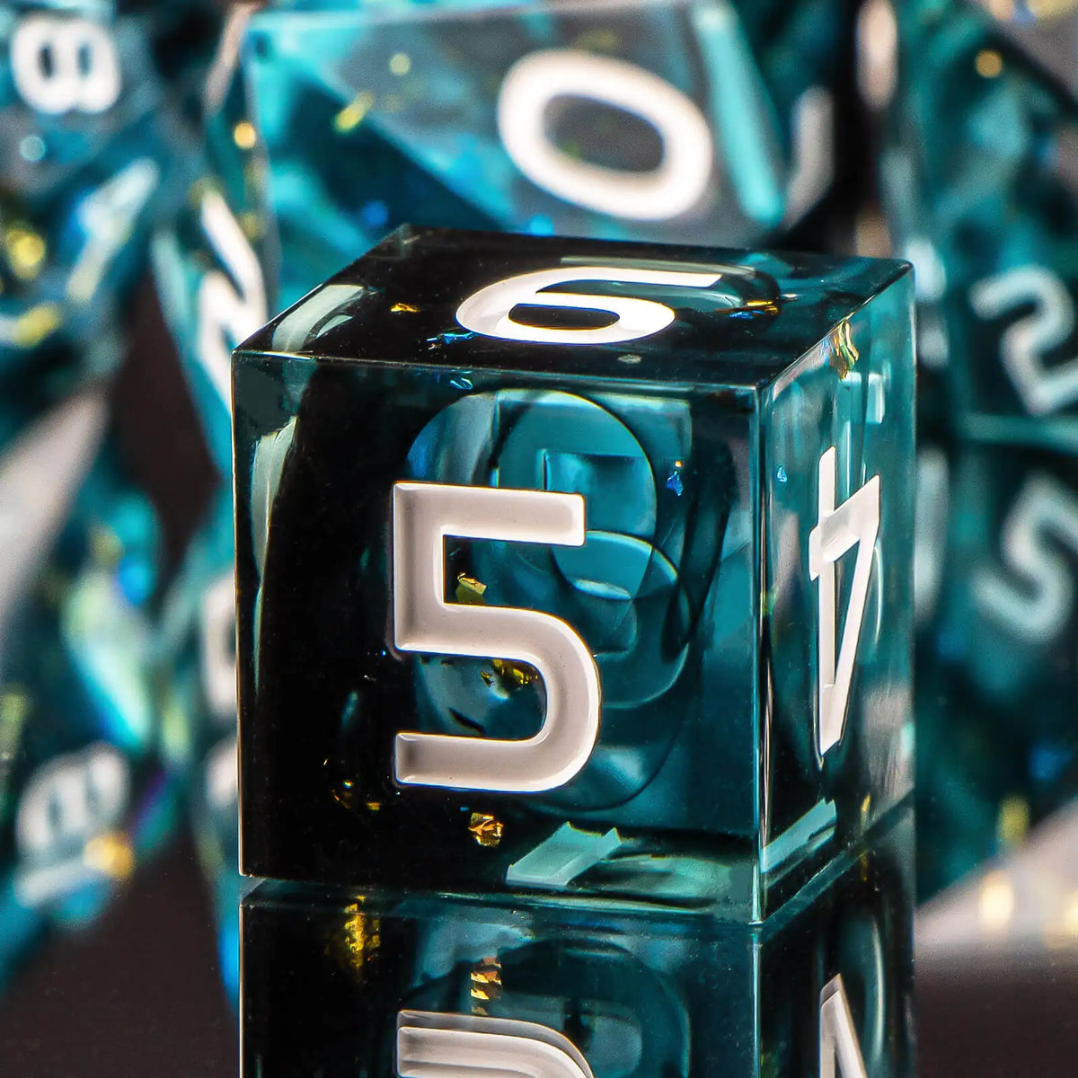 A close-up of a translucent blue resin die with the number 5, reflecting on a dark surface.