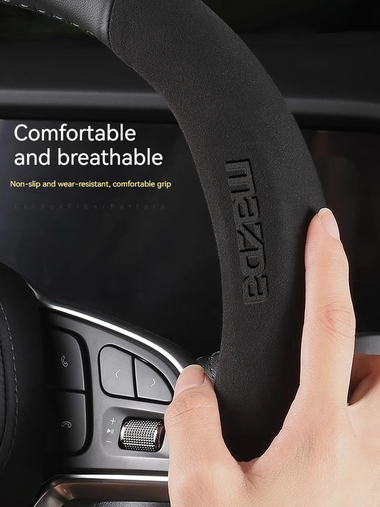 Close-up of a black leather steering wheel cover for a Mazda, highlighting the grip texture and branding.