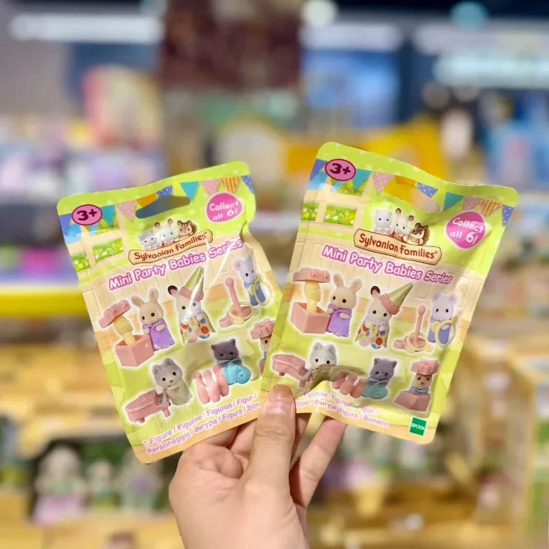 A hand holds a package of Sylvanian Families Mini Baby Party Surprise Collectible Figures.