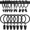 Anillos y clips de metal negro para cortinas, colgados en una barra negra.
