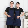 A man and a woman standing side by side wearing navy blue adjustable cotton aprons.