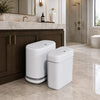 A white, modern slim rectangular trash can set with lids sitting on a marble countertop in a bathroom setting.