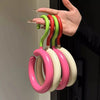 A hand holds a set of colorful, curved hooks for organizing hats and scarves.