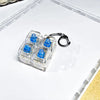 A clear plastic container holds three blue LED mechanical keychain fidget toys with custom keycaps.