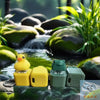 A yellow interactive fidget keychain with sound and LED lights rests on a mossy rock in a natural water feature.