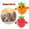 An orange singing plush toy shaped like a fruit, next to a gray bunny plush toy.