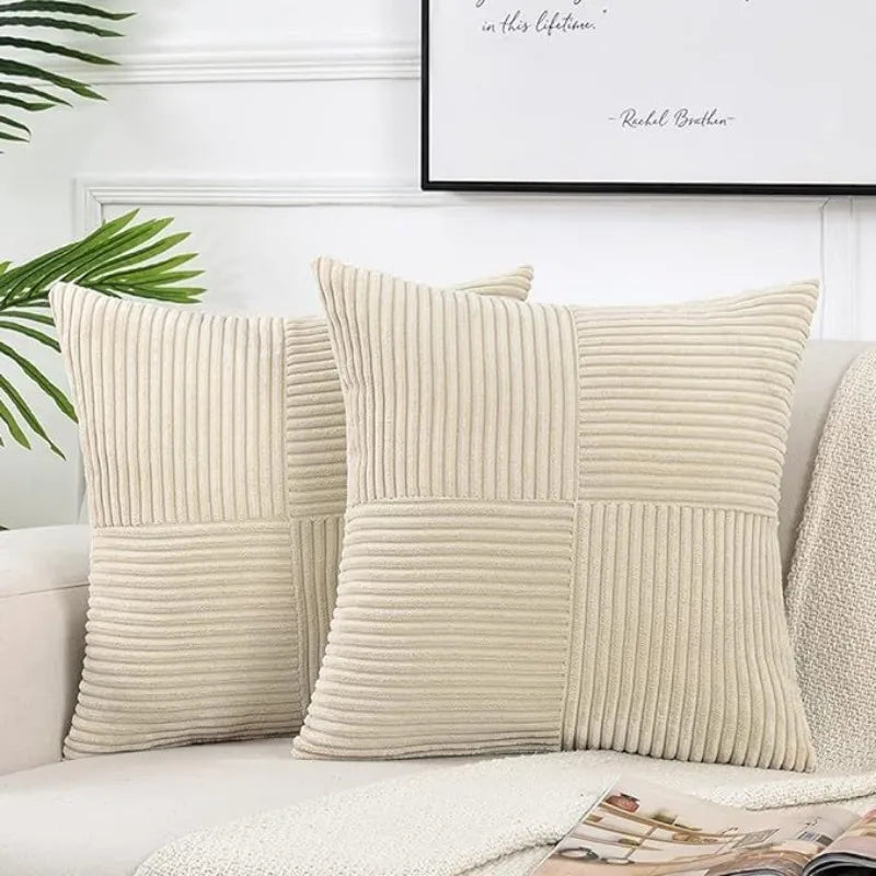 A set of two beige corduroy patchwork throw pillow covers displayed on a white sofa.