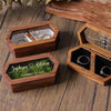 Two wooden ring boxes with engraved names and dates resting on a wooden surface.