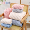 A stack of various colored plush bath towels, including pink, gray, white, and blue, displayed in a wooden frame.