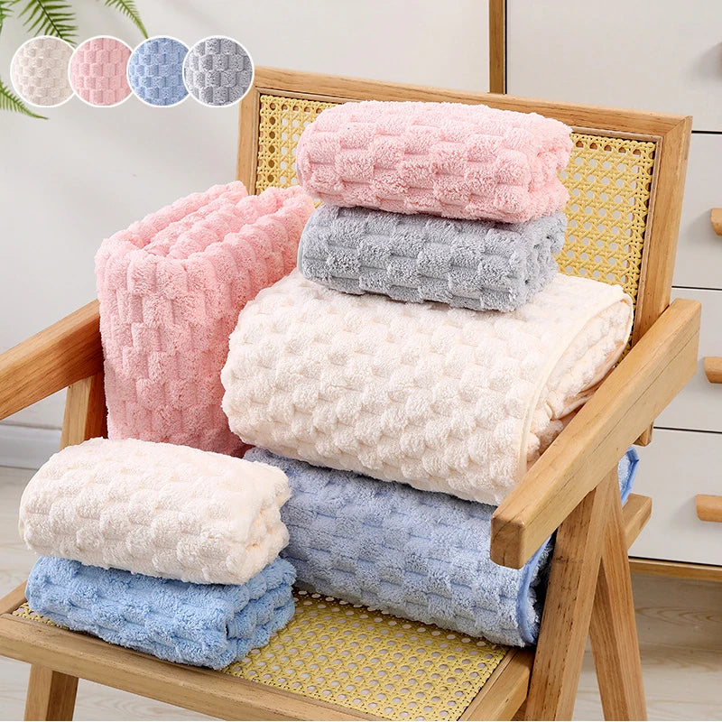 A stack of various colored plush bath towels, including pink, gray, white, and blue, displayed in a wooden frame.