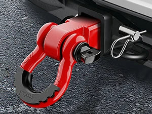 A red heavy-duty shackle hitch receiver with a D-ring and trailer pin mounted on a gray surface.