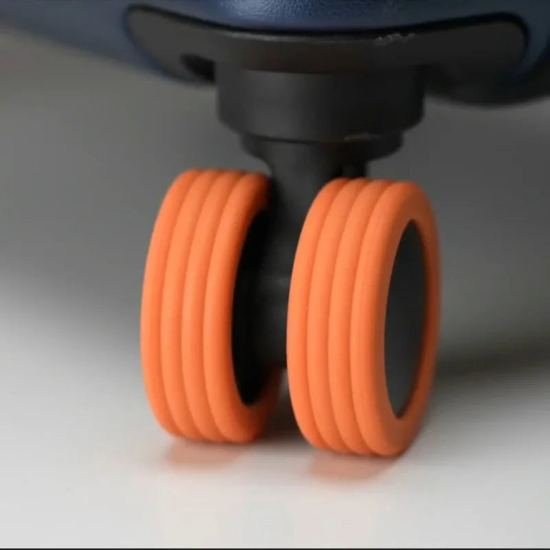 A close-up view of four orange silicone wheel protectors attached to a black caster wheel.