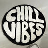 A round black carpet with white fuzzy lettering spelling out CHILL VIBES