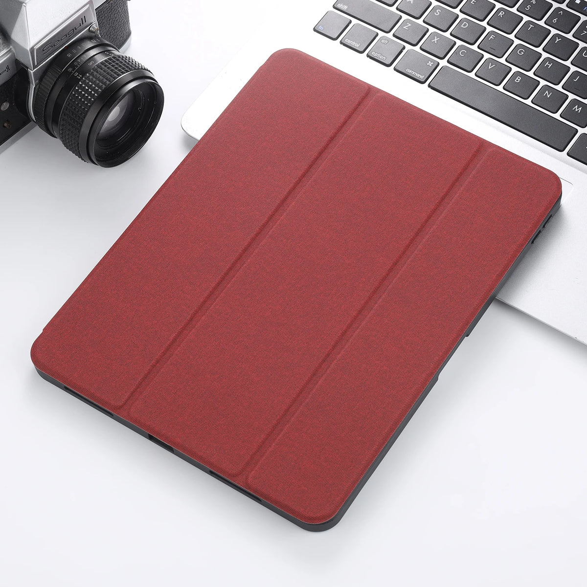 A red Retro Marble iPad Pro case with a built-in pencil holder is shown next to a silver laptop and camera.