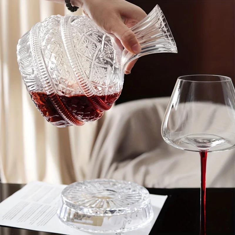 A hand pours red wine from a handcrafted crystal decanter with a rotating aerator into a glass.