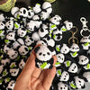 A hand holds a cluster of handmade crochet kitten keychains featuring cute panda and cartoon animal charms.