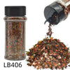 A glass jar of holographic chunky nail glitter mix with a black shaker top next to a pile of the same glitter.
