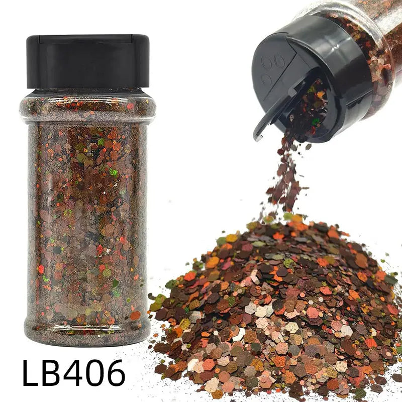 A glass jar of holographic chunky nail glitter mix with a black shaker top next to a pile of the same glitter.