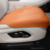 An orange breathable leather car seat cushion with a blue light accent is shown in a white vehicle interior.