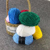 A collection of brightly colored soft 4-ply milk cotton yarn skeins in blue, pink, green, and yellow displayed in a woven bas