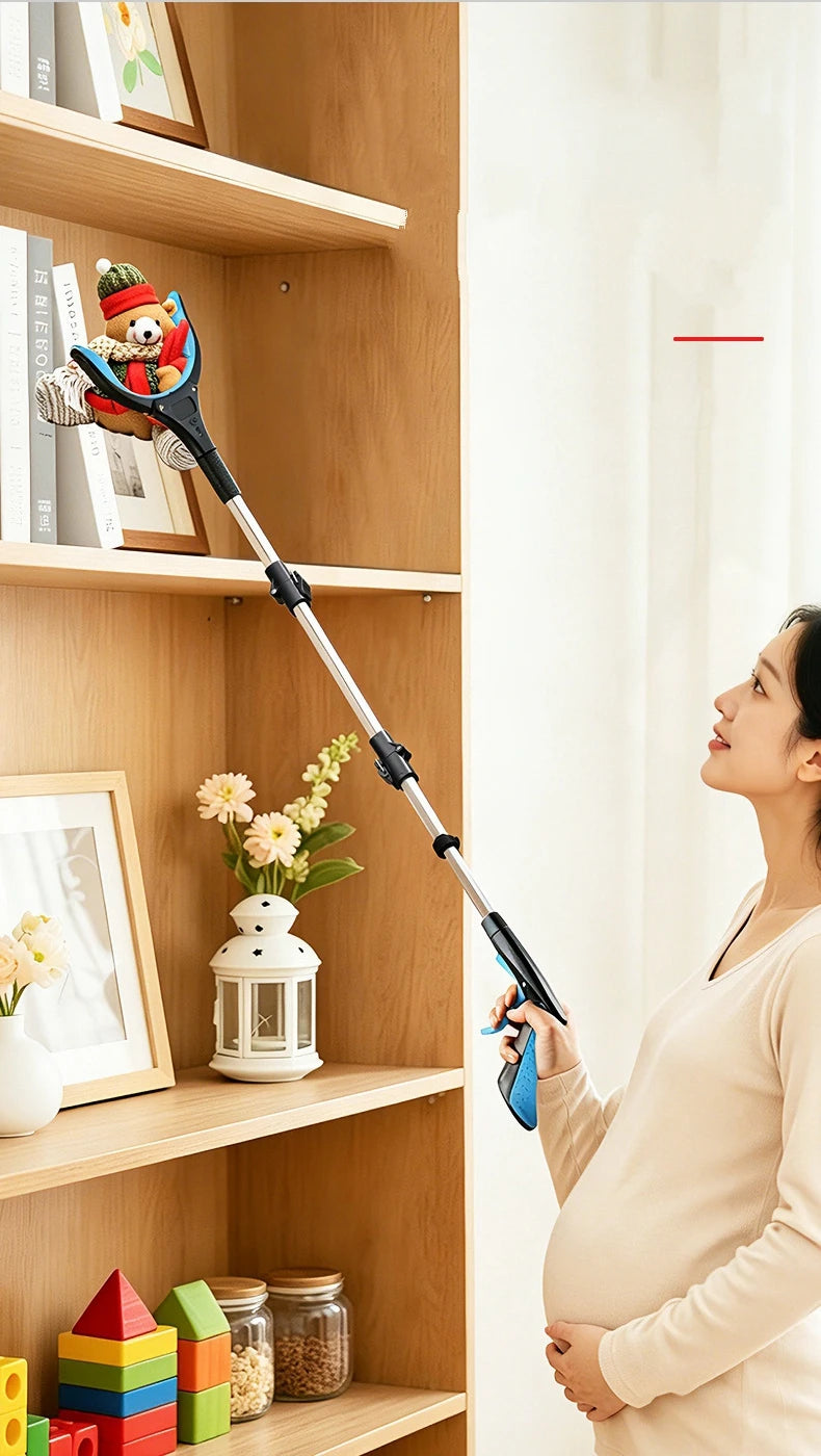 A pregnant woman holds a foldable grabber tool against a wooden shelf with various items.