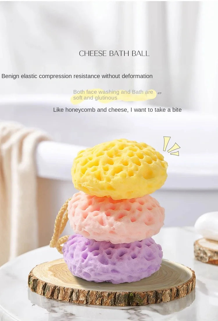 A stack of cheese bath balls in yellow, pink, and purple on a wooden surface.