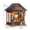 A miniature wooden Japanese tea house model featuring a tiled roof, sliding doors, and decorative elements.