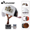 A white motorcycle helmet featuring a Boss logo and a visor, shown with accessories like a cap and leather goods.