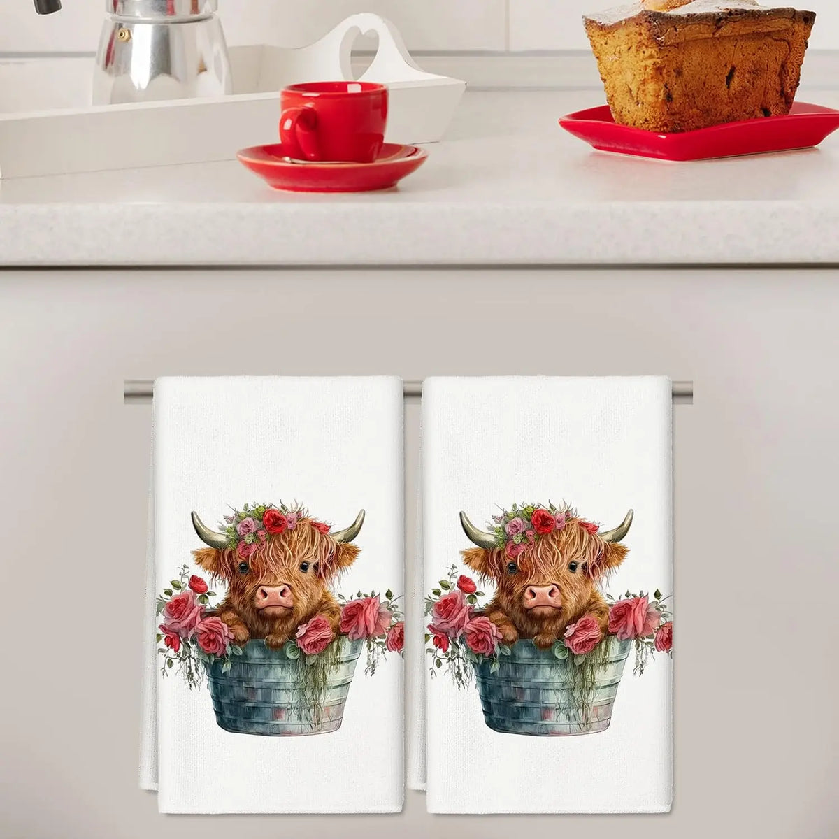 Two kitchen towels featuring watercolor illustrations of Highland cows with floral wreaths.