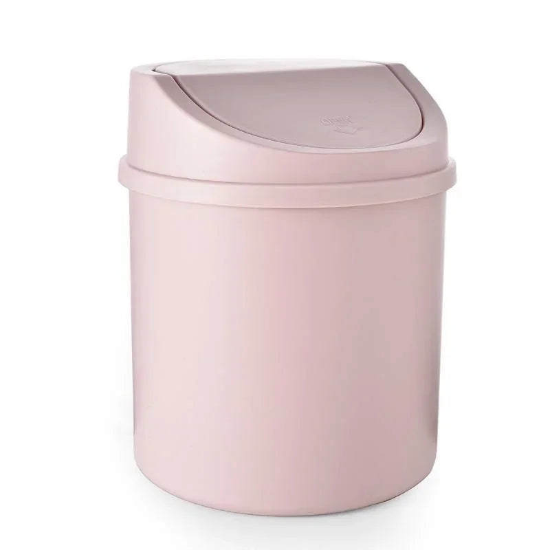 A compact, light pink desktop trash bin with a flip-top lid.