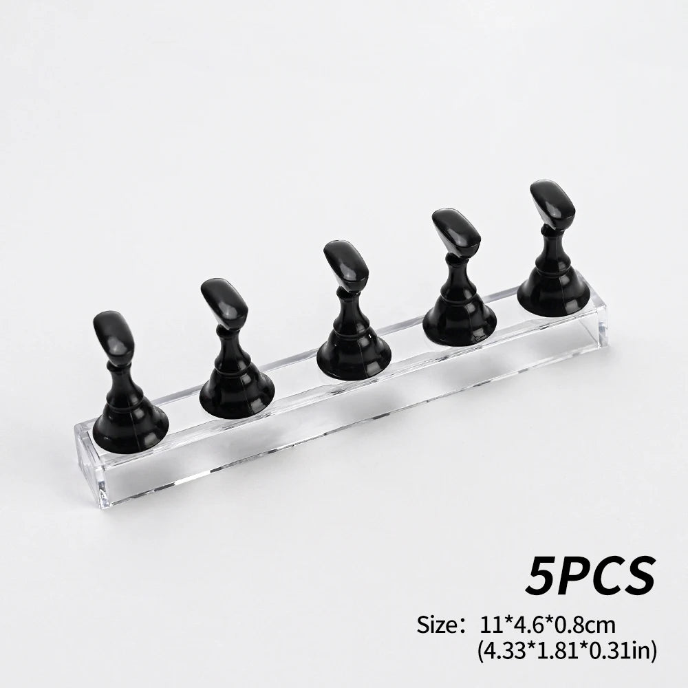 Five black reusable nail glue clay pieces displayed on a clear glass shelf.