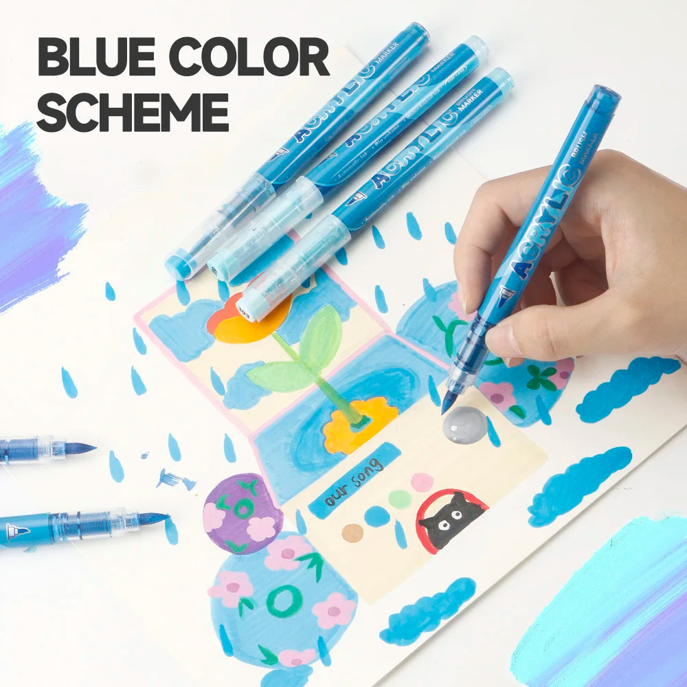 A hand holds a set of blue color scheme paint markers with soft brush tips on watercolor paper.