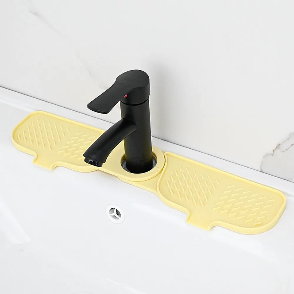 Yellow silicone sink faucet mat with a black rotating splash guard installed on a white sink.