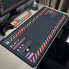 A large black mouse pad featuring a mechanical layout with colored markers and controls for gaming.