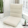 A beige foldable floor sofa cover for a single seat is displayed on a white rug next to a potted cactus.